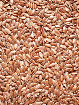 A close-up overhead shot shows a pile of flax seeds. The seeds are oval-shaped and reddish-brown in color.