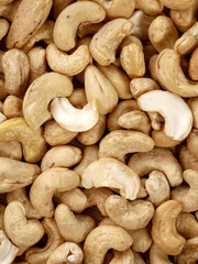 Fototapeta premium A close-up view of a pile of raw, unshelled cashews. The nuts are light brown and have a distinctive curved shape.