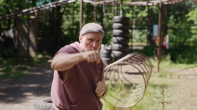 Portrait of young adult Caucasian man shadowboxing and throwing punches directly at camera at outdoor gym. Clip is ideal for fitness motivation videos and athletic training promos