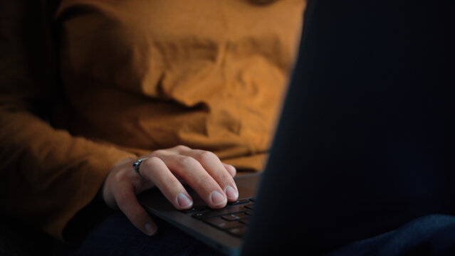Close-up of an anonymous woman's hand using a laptop, representing digital interaction, technology, online activities and everyday computer use