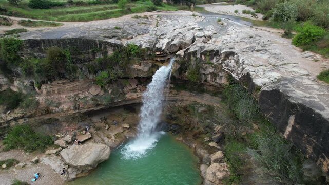 Orbital aerial shot of Salto de La Portellada waterfall on cloudy spring day. Teruel, Aragon, Spain.