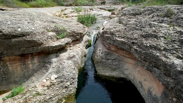 Drone footage of Charca del Molino (natural limestone pool) on sunny day. Arnes, Tarragona, Spain.