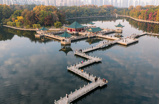Aerial view of Wuhan East Lake in autumn. Traditional pavilions and zigzag bridges rest on tranquil waters amid vibrant foliage, embodying the classical Chinese harmony between architecture and nature