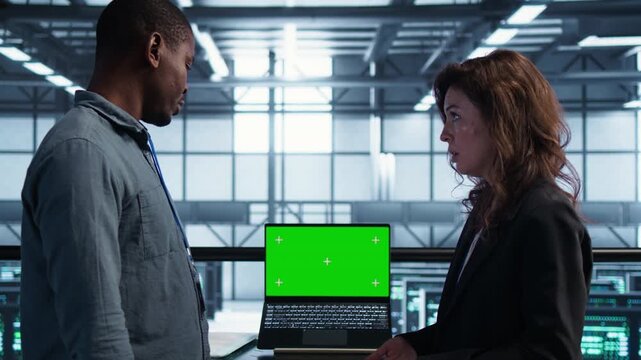 Computer scientists manage chroma key in a server room with laptop, combining screen mockup, document review and infrastructure review within a controlled technical environment.