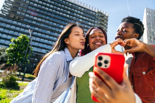Female friends take a city selfie with a heart gesture
