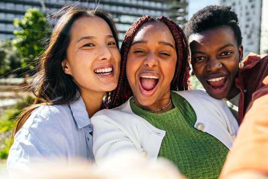 Three female friends taking a joyful selfie in the city