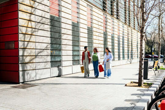 Female friend walking and chatting with shopping bag