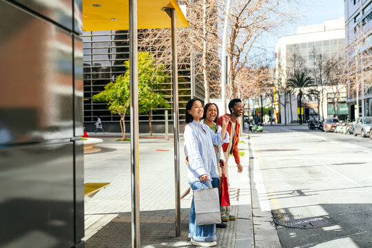 Female friend waiting at bus stop in sunny city street