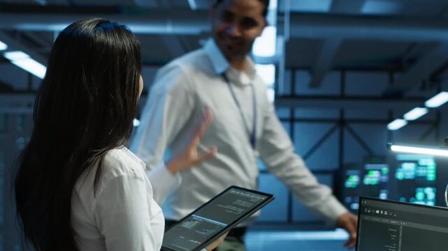 Computer scientist checks infrastructure performance inside a server room with a tablet, connecting performance oversight and system reliability with enterprise infrastructure work