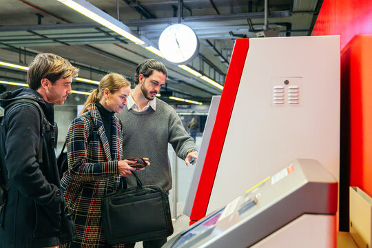 Business travelers buying ticket at station self-service kiosk