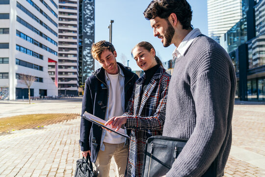 Business coworking team review notes in modern city plaza