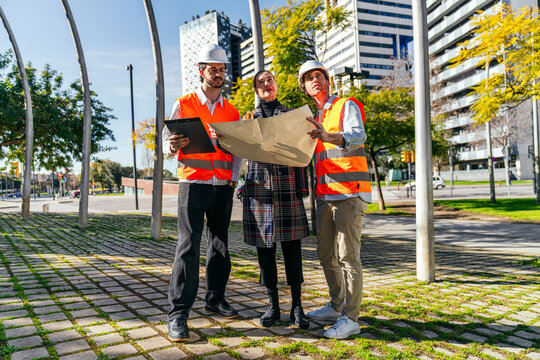 Construction team reviewing site plan in modern city park