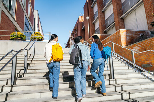 Student group walking up campus stairs between buildings