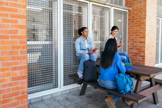 University students chatting at campus picnic table outdoors