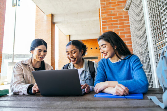 University students collaborating on laptop at campus table