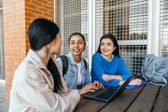 University students studying outdoors on campus with laptop