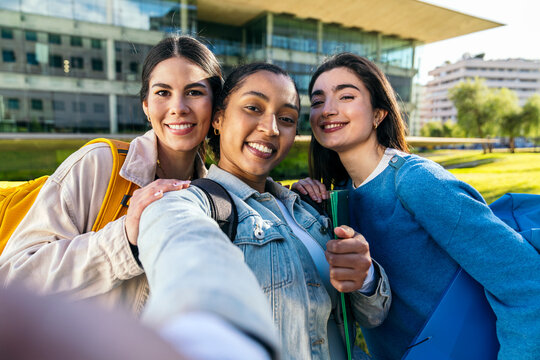 Diverse university students taking selfie on campus lawn