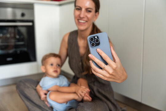 Mother and son taking a smartphone selfie in home kitchen
