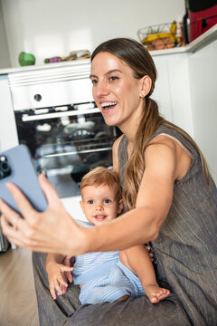 Mother and baby son taking a smartphone selfie in kitchen