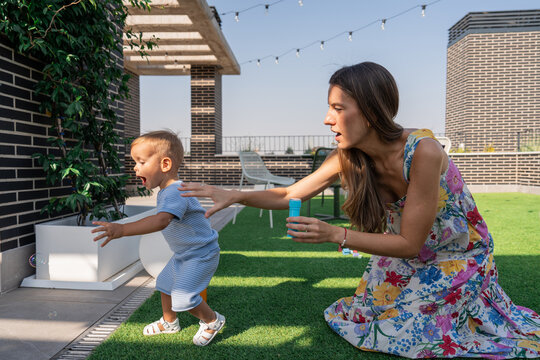 Mother playing with toddler son on sunny rooftop terrace