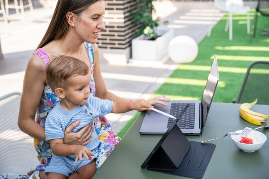 Mother and son using laptop outdoors for remote work