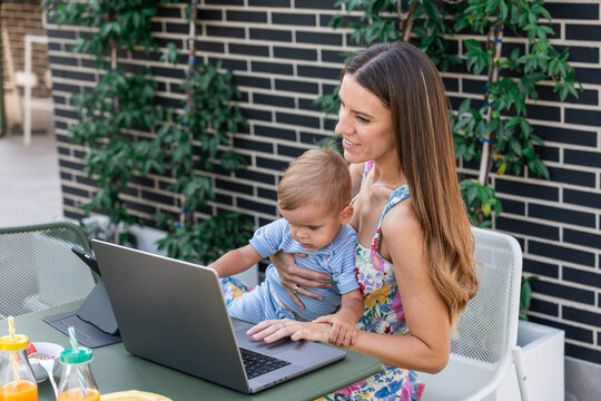 Mother and son using laptop on patio during remote work