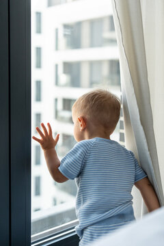 Caucasian boy looking out apartment window in daylight