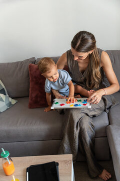 Mother and son play alphabet letters on sofa at home
