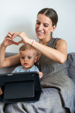 Mother and son using tablet on sofa at home together