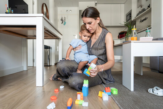 Mother and son play with building blocks on kitchen floor