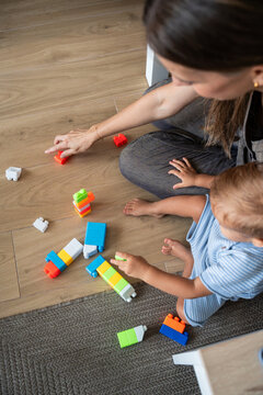 Mother and son playing with building blocks on floor