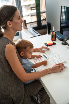 Mother and son using computer at home office desk together