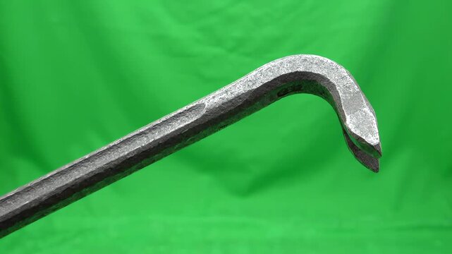 Heavy duty steel crowbar tool rotating slowly on a bright green screen background for chroma key compositing