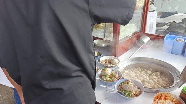 Indonesian Bakso Vendor Pouring Hot Broth and Meatballs into Bowl - 9s