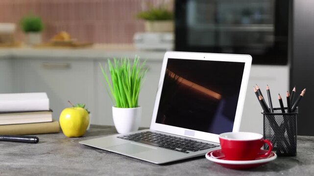 Workplace with laptop, stationery, cup, apple, decor and books on grey table indoors, closeup. Camera moving left