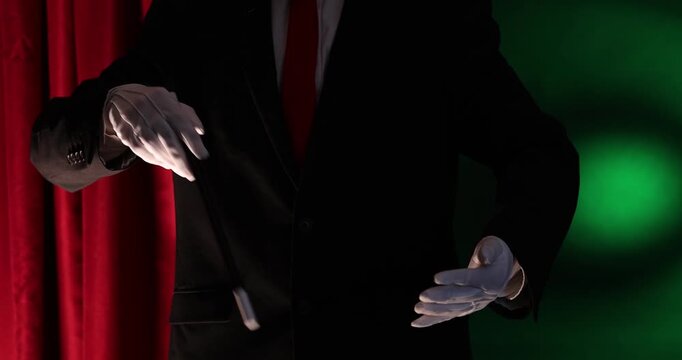 Magician showing trick with wand on stage, closeup