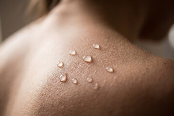Fototapeta premium Clear water droplets resting on human shoulder skin after sweating
