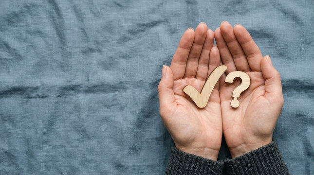 Hands holding a wooden checkmark and a question mark icon representing problem solving, decision making, and answering frequently asked questions.