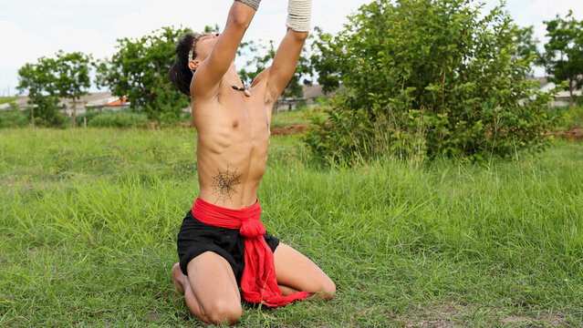 Shirtless Muay Thai Fighter Performing Traditional Wai Kru Ritual Outdoors