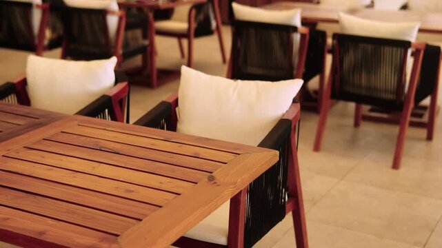 Tranquil empty cafe interior showcases a stylish blend of modern design and rustic charm. Rows of wooden tables and chairs line the space highlighting minimalist elegance. Food and beverage industry.