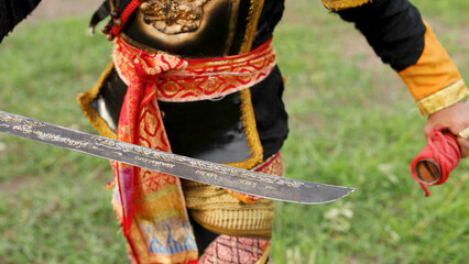 Obraz premium Close-up of Asian Warrior Holding Engraved Steel Sword in Ornate Armor