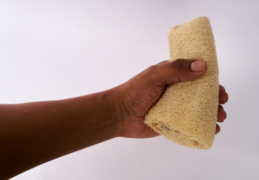 Human hand holding a natural loofah sponge isolated on white background
