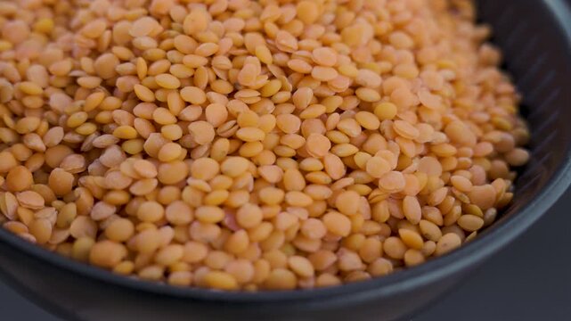 Macro zoom in on dry orange lentils in black bowl low key 4k