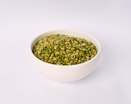Ceramic bowl filled with dried split green peas isolated on white background
