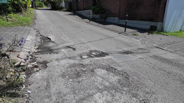 Damaged road surface with potholes on a street in South Bali near Uluwatu, Indonesia