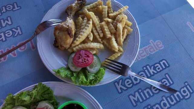 Fried chicken with crinkle-cut fries and fresh salad at a Bali warung