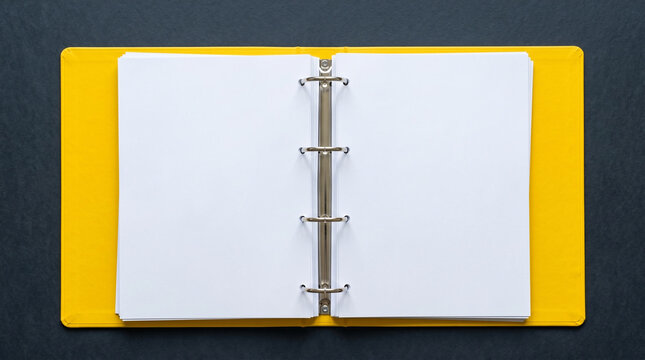 Top view of an open yellow three-ring binder with blank paper.