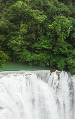 Fototapeta premium Majestic Shifen Waterfall in Pingxi District, New Taipei City. A popular natural tourist attraction in Taiwan featuring powerful cascading water and lush green foliage.