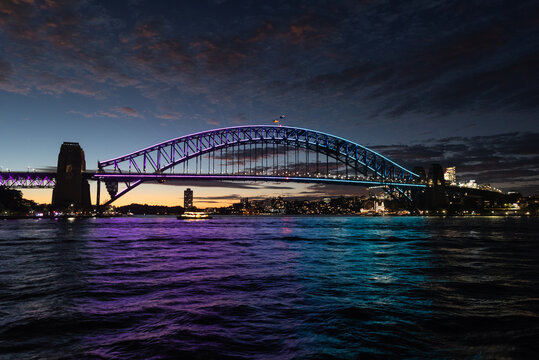 Sydney Harbour bridge just after sunset and illuminated with purple and blue lights. Sydney, New South Wales, Australia.