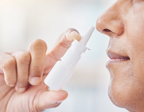 Hand using a plain nasal spray bottle at the nose for allergy and rhinitis relief